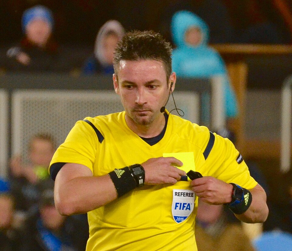 Árbitro mostrando tarjeta amarilla en un partido intenso